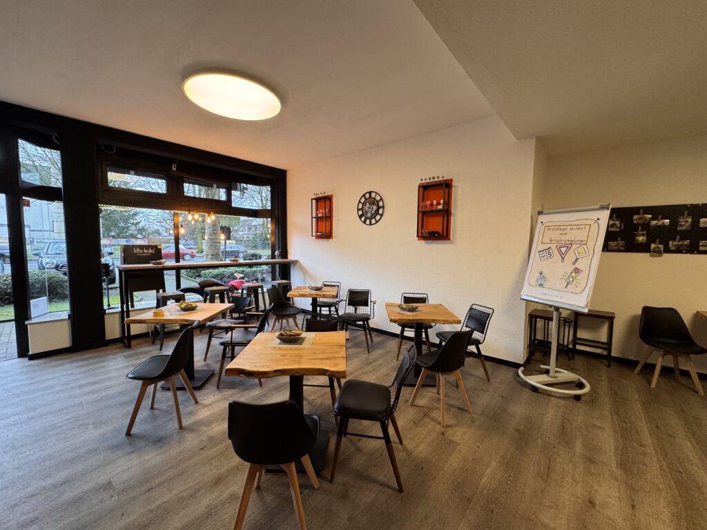 Heller Theorieraum der Fahrschule mit modernen Tischen, Flipchart und Wanddekoration.