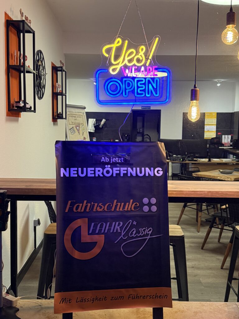 Schild mit Neueröffnung und Slogan Mit Lässigkeit zum Führerschein in der Fahrschule Fahrlässig