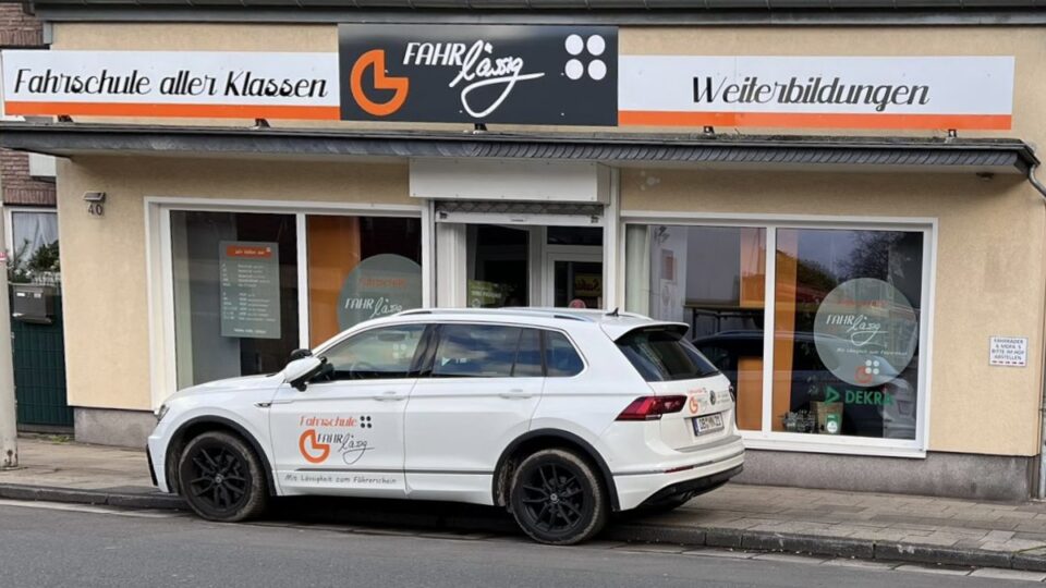 Fahrschulfahrzeug der Fahrschule FAHRlässig vor dem Standort mit Beschilderung „Fahrschule aller Klassen“ und „Weiterbildungen“ geparkt.